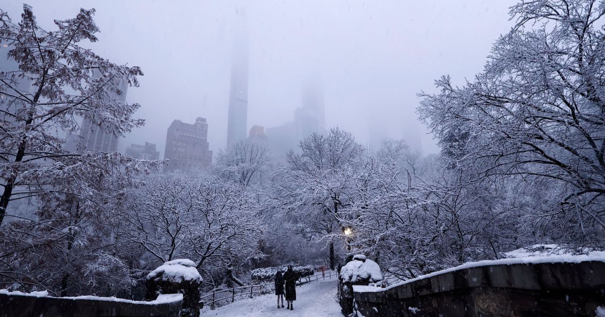 Pessoas caminham sobre a Ponte Gapstow no Central Park durante uma nevasca em 14 de dezembro de 2025